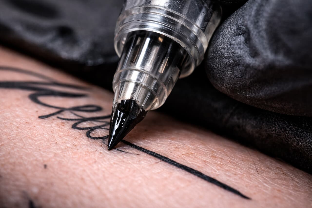 Nadelspitze einer Tätowiermaschine in Nahaufnahme auf Haut